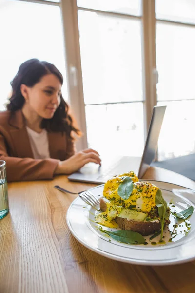 Woman Working Laptop Cafe Eating Fresh Vegetarian Toast Avocado Eggs — Stock Photo, Image