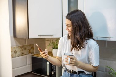 Sabah kahvesi içen bir kadın. Mutfakta internette sörf yapıyor. E-postaları kontrol ediyor.