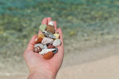 Deniz kıyısında oturan ve taşlarla oynayan bir kadın. yaz tatili