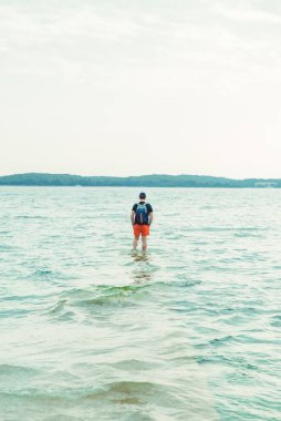 Sahildeki deniz suyunda duran adam boşluğu kopyalıyor.