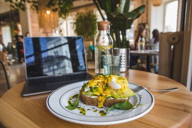Lokantada avokado ve yumurtalı tost. Kahverengi renkler. Boşluğu kopyala.