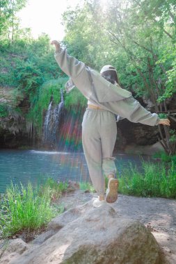 Kadın yürüyüşçü, şelale yaz yolculuğu konseptini zevkle izliyor.