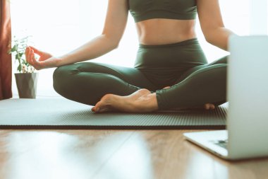 Kadın bilgisayarın yanında yoga yapıyor çevrimiçi öğrenim uzaktan spor eğitimi veriyor.
