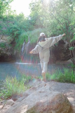 Kadın yürüyüşçü, şelale yaz yolculuğu konseptini zevkle izliyor.
