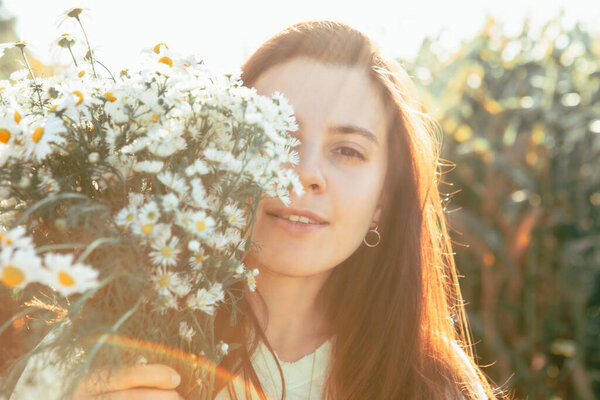 portrait of adult woman with chamomile flowers bouquet sunset warm colors