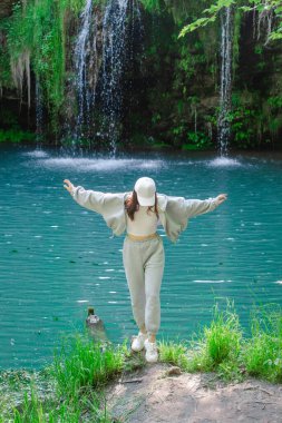 Kadın yürüyüşçü, şelale yaz yolculuğu konseptini zevkle izliyor.