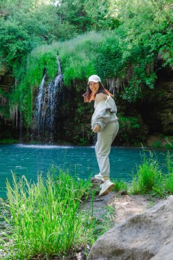 Kadın yürüyüşçü, şelale yaz yolculuğu konseptini zevkle izliyor.