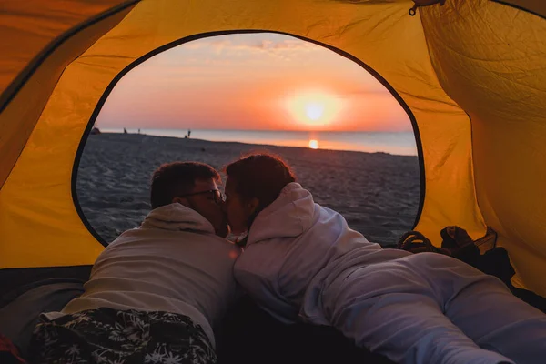 couple sleeping in camping tent looking at sunrise. hiking concept. sea beach