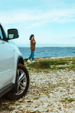 Deniz kenarında duran kadın deniz aracı seyahat konseptine bakıyor. off road