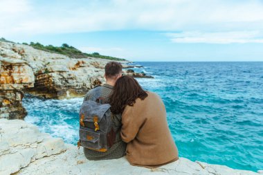Uçurumda oturup denize bakan çift. büyük dalgalar.