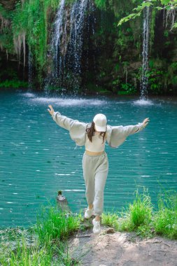 Kadın yürüyüşçü, şelale yaz yolculuğu konseptini zevkle izliyor.