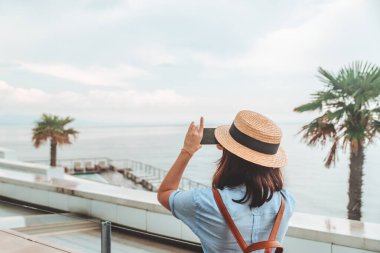 Kadın gezgin telefonunda fotoğraf çekiyor. Deniz sahili fotokopi alanı.