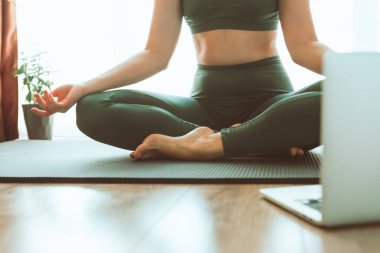 Kadın bilgisayarın yanında yoga yapıyor çevrimiçi öğrenim uzaktan spor eğitimi veriyor.