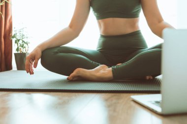 Kadın bilgisayarın yanında yoga yapıyor çevrimiçi öğrenim uzaktan spor eğitimi veriyor.