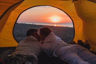 Kamp çadırında uyuyan çift güneşin doğuşunu seyrediyor. Yürüyüş konsepti. deniz plajı