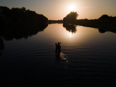 Nehirdeki kadın silueti Gün batımı fotokopi uzayında