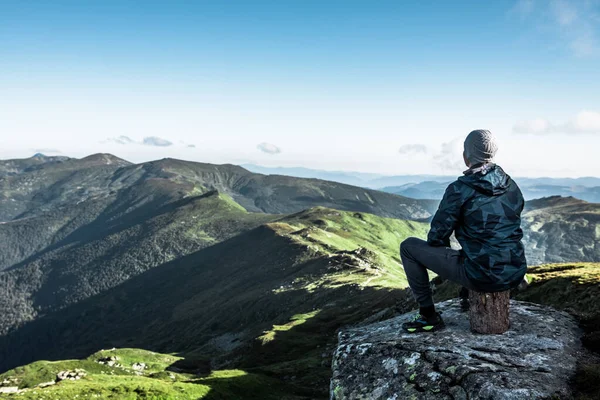 男は山の頂上に座って景色を楽しんでいる コピースペース — ストック写真