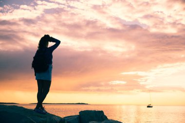 Sırt çantalı kadın gün batımını seyrediyor. Boşluğu kopyala