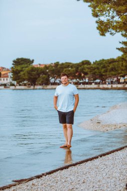 Hırvatistan 'da yaz akşamları deniz kıyısında gezen bir adam. tatil kavramı