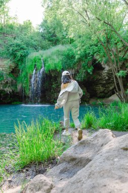 Kadın yürüyüşçü, şelale yaz yolculuğu konseptini zevkle izliyor.