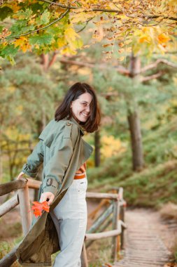 Genç, gülümseyen bir kadın güz havasının tadını çıkarıyor. kıyafet