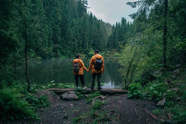 Caminhantes Casal Capa Chuva Amarela Olhando Para Mochileiros Lago Montanha — Fotografia de Stock