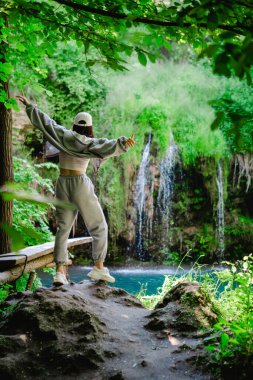 Kadın yürüyüşçü, şelale yaz yolculuğu konseptini zevkle izliyor.