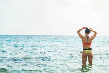 Güçlü seksi kadın, midilli kuyruğu yapıyor. Deniz suyunun arkasında dikiliyor.