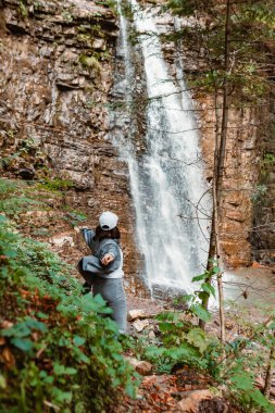 Kadın yürüyüşçü şelale fotokopi alanının keyfini çıkarıyor