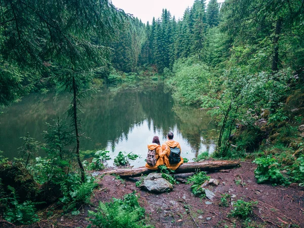 Пара Туристів Жовтому Плащі Дивлячись Рюкзаки Гірському Озері — стокове фото