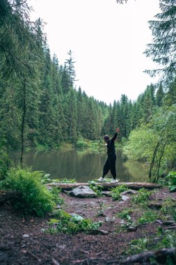 Kadın dağlardaki vahşi göl manzarasının tadını çıkarıyor.