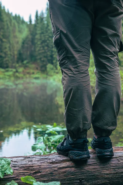 hiking concept wet legs in sneakers near lake in forest copy space