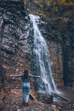 Şelale fotokopi alanına bakan günlük elbiseli bir kadın.