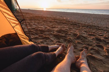 Çiftler kumsalda oturup gün batımını seyrediyorlar. Boşluğu kopyala.