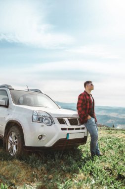Dağın tepesinde SUV arabasının yanında duran bir adam. kopyalama alanı. yaz günü