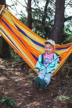Küçük kız hamakta eğleniyor.
