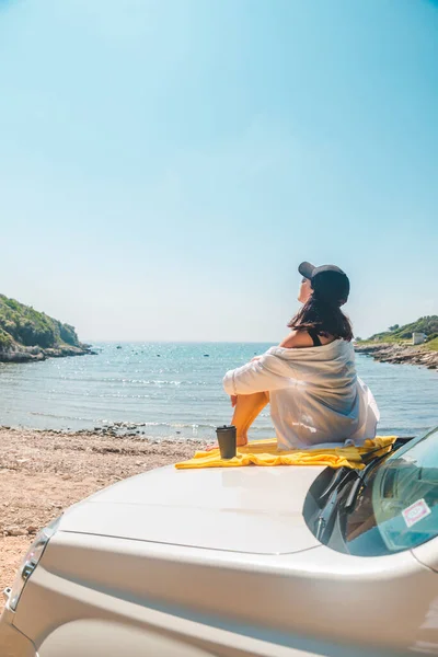 快乐的女人在海上夏季海滩坐在汽车引擎盖度假的概念 — 图库照片