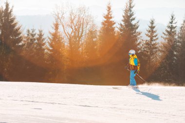 Kadın arka planda kış yamaçlarında kayak yapıyor.