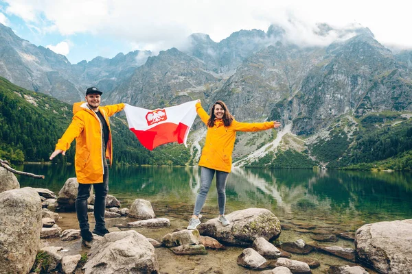 폴란드 국기를 노란색 비옷을 부부가 해변에 — 스톡 사진