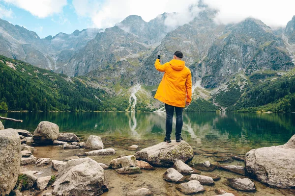 Hombre Impermeable Amarillo Tomando Fotos Teléfono Del Lago Las Montañas — Foto de Stock