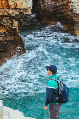 Adam tırmanıyor. Kayalık kenar. Deniz manzarasının tadını çıkarıyor. seyahat kavramı