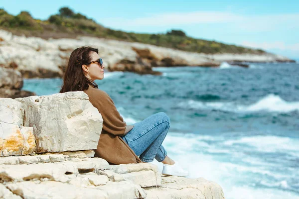 Uçurumun Kenarında Oturup Deniz Manzarasının Keyfini Çıkaran Kadın Rüzgarlı Hava — Stok fotoğraf