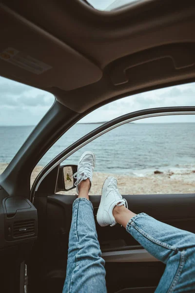 woman resting in car parked at sea beach. summer vacation