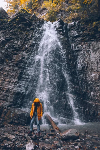 秋天瀑布远足时穿着黄色雨衣的女人 — 图库照片