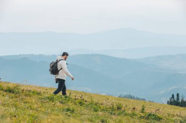 Sırt çantalı bir adam sonbahar mevsiminde dağlarda yürüyüş yapıyor.