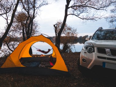 Göl kıyısındaki hamakta yatan kadın. Sonbahar kampı konsepti. Boşluğu kopyala