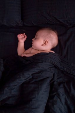 Huzurlu bebek başucundaki koyu renkli yatakta uyuyor.