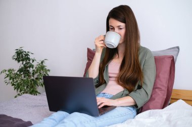 Genç bir kadın kahve içiyor ve interneti arıyor, online alışveriş yapıyor, çalışıyor ya da okuyor..