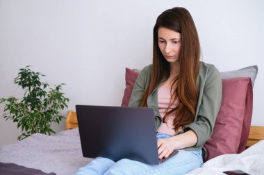 Evde dizüstü bilgisayarla çalışan genç bir kadın. Samimi çalışma alanı. 