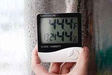 Measurement of air temperature, dew point, humidity with a device (hygrometer), against a background with condensation on the glass, high humidity clipart